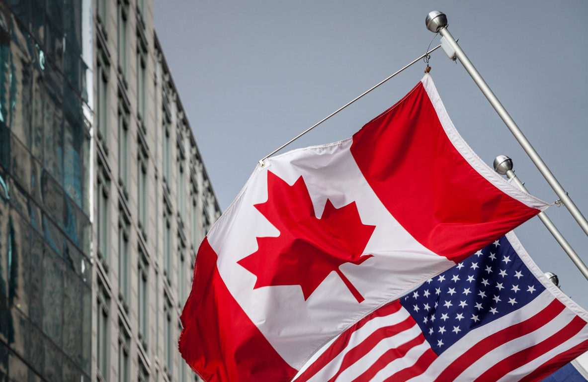 photo of Canadian and US flags hanging off a building